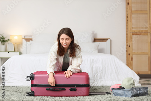 Young woman packing suitcas...