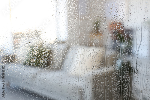 фотографія Water droplets on glass against blurred sofa in living room, closeup