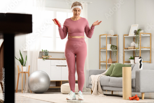 Quadro su tela Sporty mature woman with menopause measuring weight at home