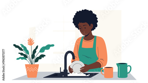 Young African American woman wearing an apron and washing a plate in the sink with a potted plant on the kitchen counter.