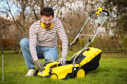 Young man with lawn mower o...