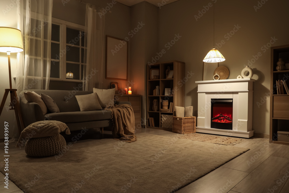 Fototapeta premium Interior of dark living room with fireplace, sofa and glowing lamps at night
