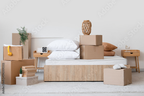 Fotografía Bedroom interior with moving boxes on bed in new home, cozy minimalist room with