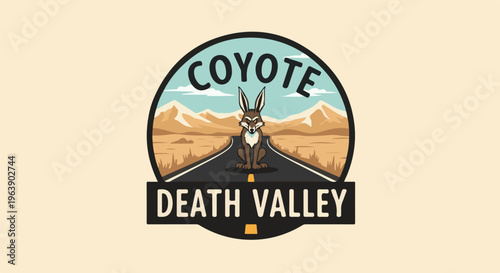 A coyote sits on a desert road in Death Valley under mountains