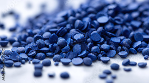 Close up of dark blue plastic masterbatch granules in multiple sizes on white surface