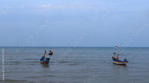Two fishing boats made of wood anchored on the north coast of Tuban, East Java, Indonesia at dusk.