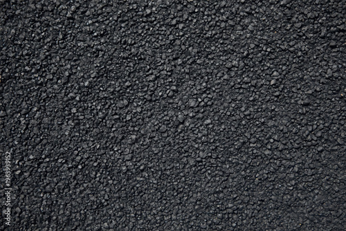 Close up view of dark grey asphalt road surface texture with small crushed stone aggregate