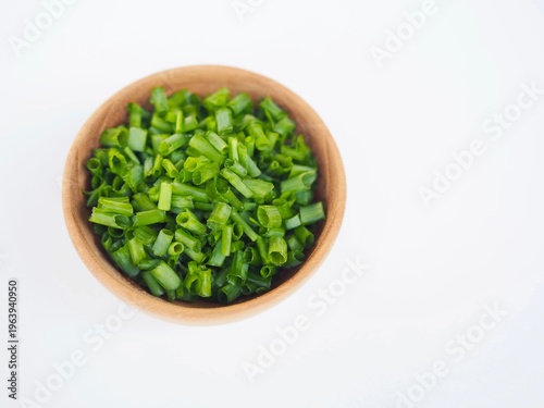 Foto Fresh scallions, finely chopped, are placed in a wooden bowl on a white surface