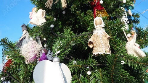 Colorful ornaments sparkle on a beautifully decorated winter tree. The sunlight highlights each unique piece, creating a joyful atmosphere during the holiday season