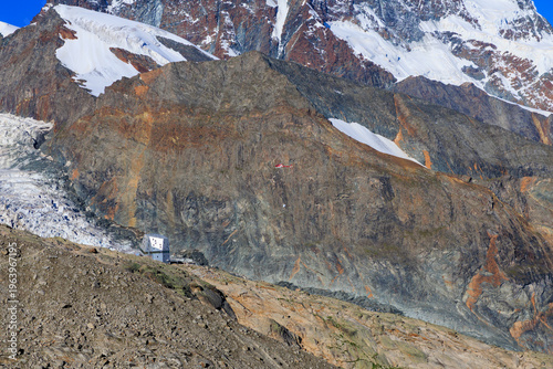 Helicopter delivering supplies to mountain hut Monte Rosa Hut at Monte Rosa massif with mountain glacier panorama in Pennine Alps, Switzerland