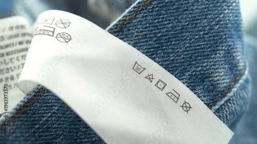 Close up of clothing care label on denim fabric with washing symbols.