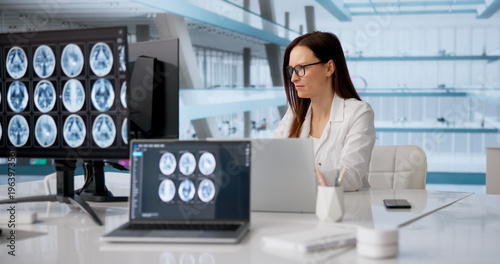 Foto Female Neurologist Analyzing Brain MRI On Computer Screen