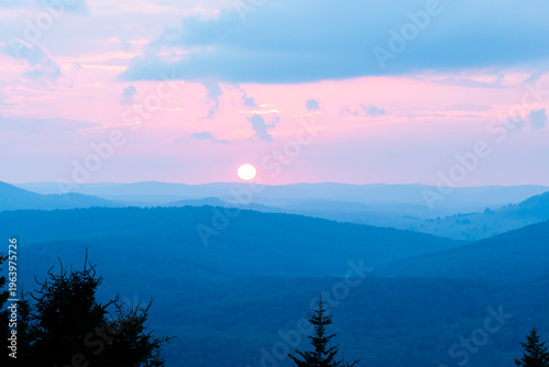 sun setting over rows and rows of blue ridge mountains in the distance and threatening to else over the horizon soon