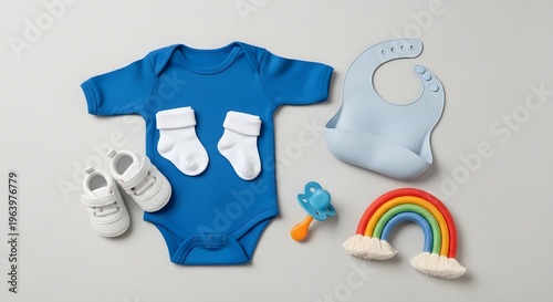 Baby shower gifts, blue onesie, socks, shoes, bib, toys on gray background