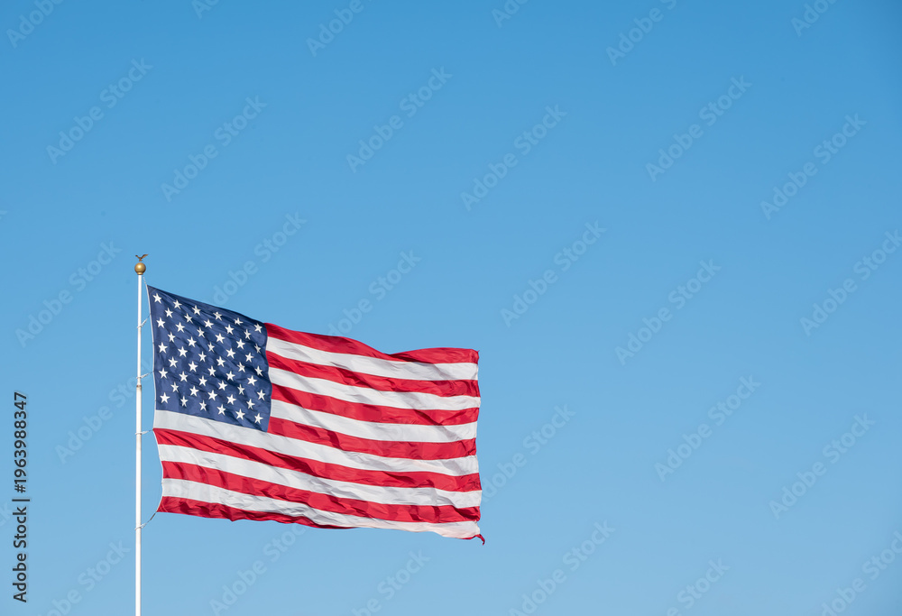 Fototapeta premium United States Flag Waving in Wind on Clear Blue Sky Background