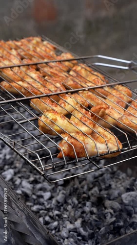 Delicious chicken frying on barbecue grill grate outdoor. Seasoning falling on fresh grilled chicken wings. Summer party food ideas. BBQ Juicy roasting chicken grill legs on grill grate 