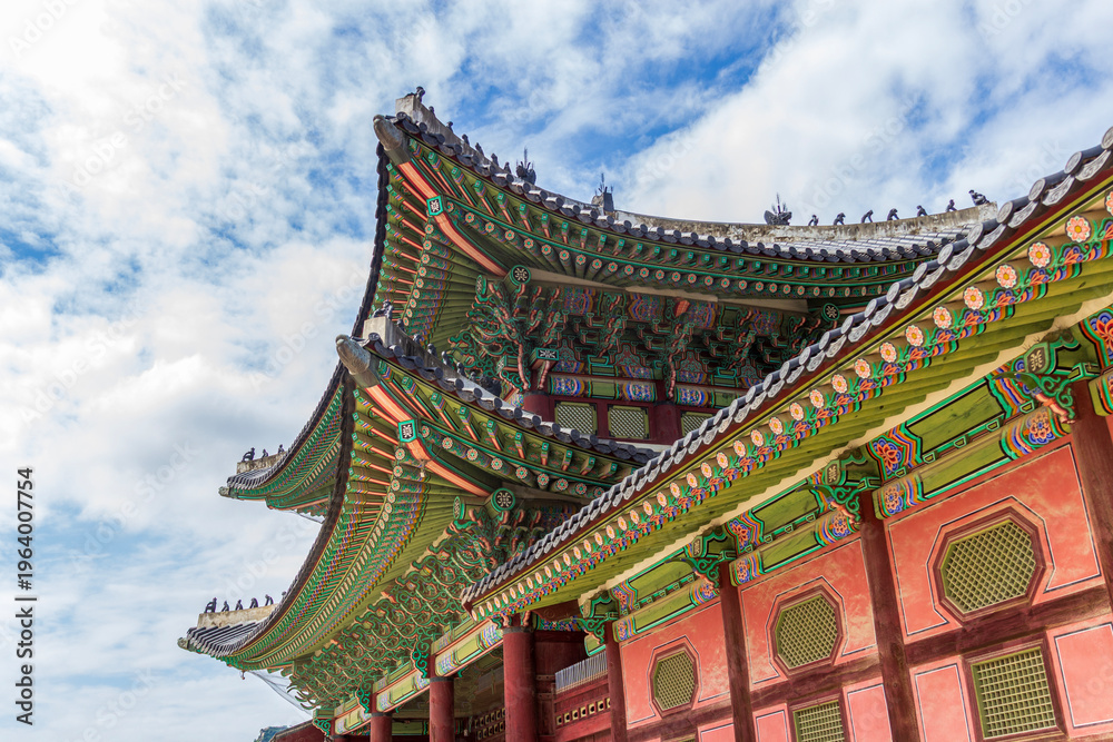 Obraz premium Majestic Korean palace architecture with symmetrical stone courtyard and layered tiled roof under dramatic sky, traditional Asian heritage landmark, cultural travel destination concept