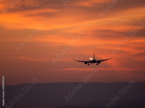 Airplane landing silhouette at sunset dramatic sky travel aviation concept