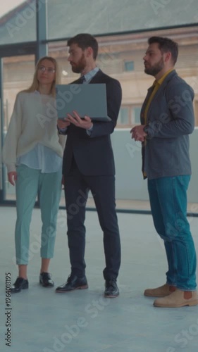Real estate professionals collaboratively inspecting office space using laptops and discussing details