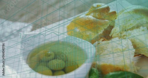 Camera shifting downward and left showcasing food bowl basil citrus, torn bread under teal grid