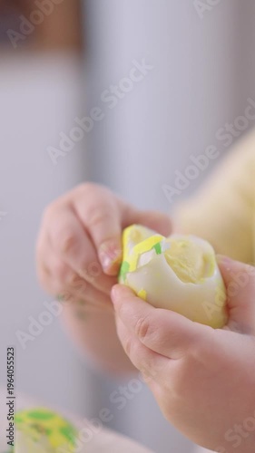Little hands peel a soft-boiled egg. Fingers carefully crack the shell. White yolk peeks through the opening. Gentle, curious, focused child. Perfect for kitchen scenes or food prep