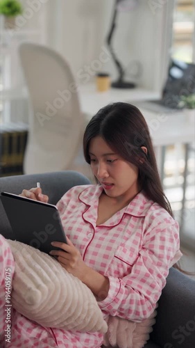 Asian adult woman freelance designer student drawing writing digital art learning online tablet stylus home comfortable sofa casual pajamas studying working relaxation creative content creation