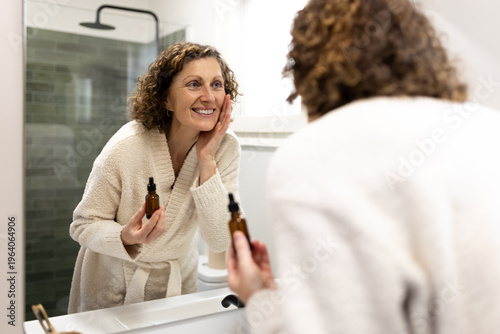 Woman applying serum to skin reflecting in mirror