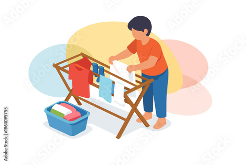 Young boy hanging clothes on a drying rack indoors.