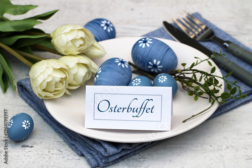Osterbuffet Gedeck für Gastronomie und Catering-Marketing – Gedeckter Tisch mit Blau-Weißer Osterdekoration und einer Karte mit dem Schriftzug Osterbuffet auf einem weißen Teller.