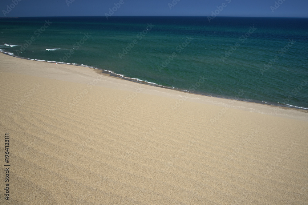 Fototapeta premium 広々とした波紋のある白い砂浜と水平線の見える青い海の風景