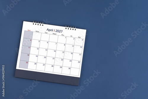 April 2027 Monthly desk calendar on blue color background, Position with copy space. Flat Lay.
