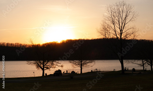Sunset at the lake, people fishing, picnic tables, silhouette
