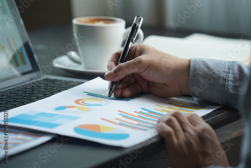 Fotografía Businessman hands writing on business documents with financial charts and coffee on desk