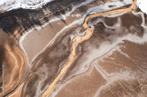 Drone aerial view of dried lake bed with melting snow and exposed shoreline. Abstract textures and environmental concept of drought and changing climate conditions
