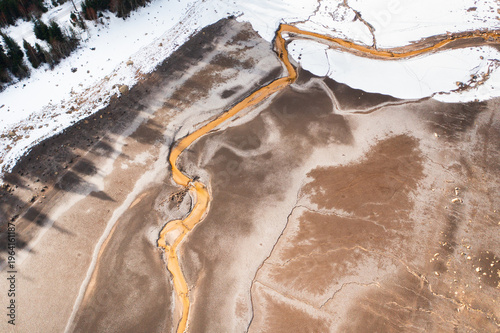 Top down aerial drone view of dried lake bed with abstract natural patterns and winding stream. Earth texture and environmental concept of drought and water shortage