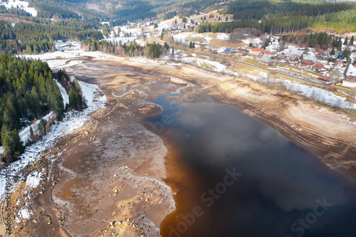Drone aerial view of dried lake bed with exposed shoreline, sand formations and natural patterns. Environmental concept of drought and low water levels