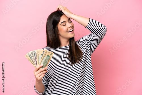 Картината върху платно Young Brazilian woman taking a lot of money isolated on pink background has real