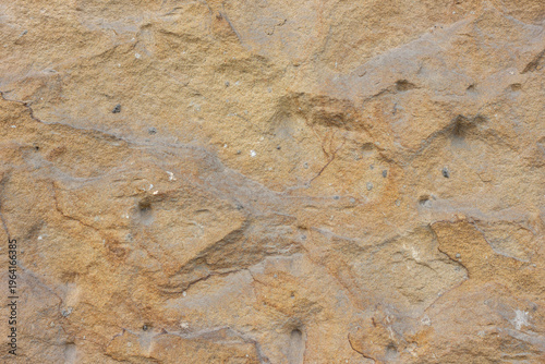 Foto Textured surface of natural sandstone rock with variations in color and pattern,