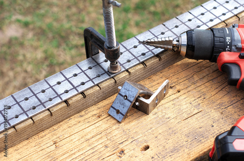 Making fence brackets. Workpieces, clamps, and a screwdriver on a workbench. Drilling holes in metal.