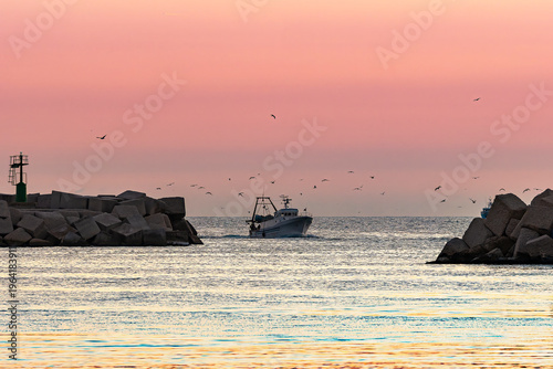 Fishing boat leaving Sciacca harbor at sunset
