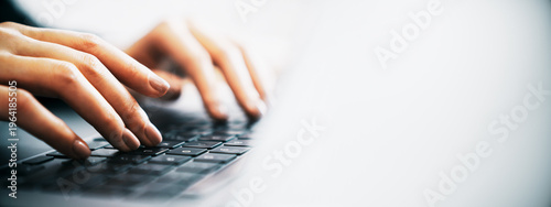 Fotografie Close-up of person's hands typing on a laptop keyboard with bright empty background creating clean modern copy space for design and communication