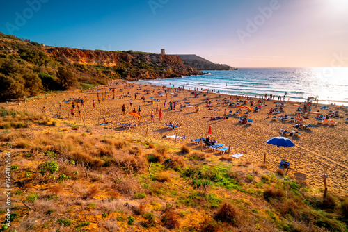 Golden Bay beach in Malta with tourists at sunset.