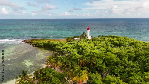 Aerial drone footage of Ilet du Gosier island near Pointe-à-Pitre, Guadeloupe. Scenic tropical landscape with white sandy beach, turquoise Caribbean Sea and iconic lighthouse. Popular travel destinati