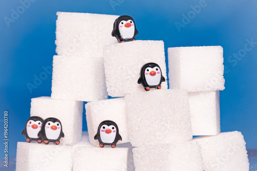 Toy penguins perched on sugar cubes as they race to the top