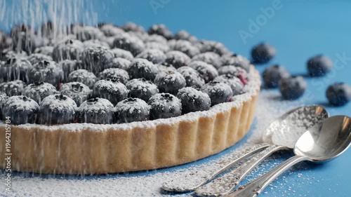 Close-Up of a Fresh Blueberry Tart Being Dusted With Powdered Sugar, Served With Spoons