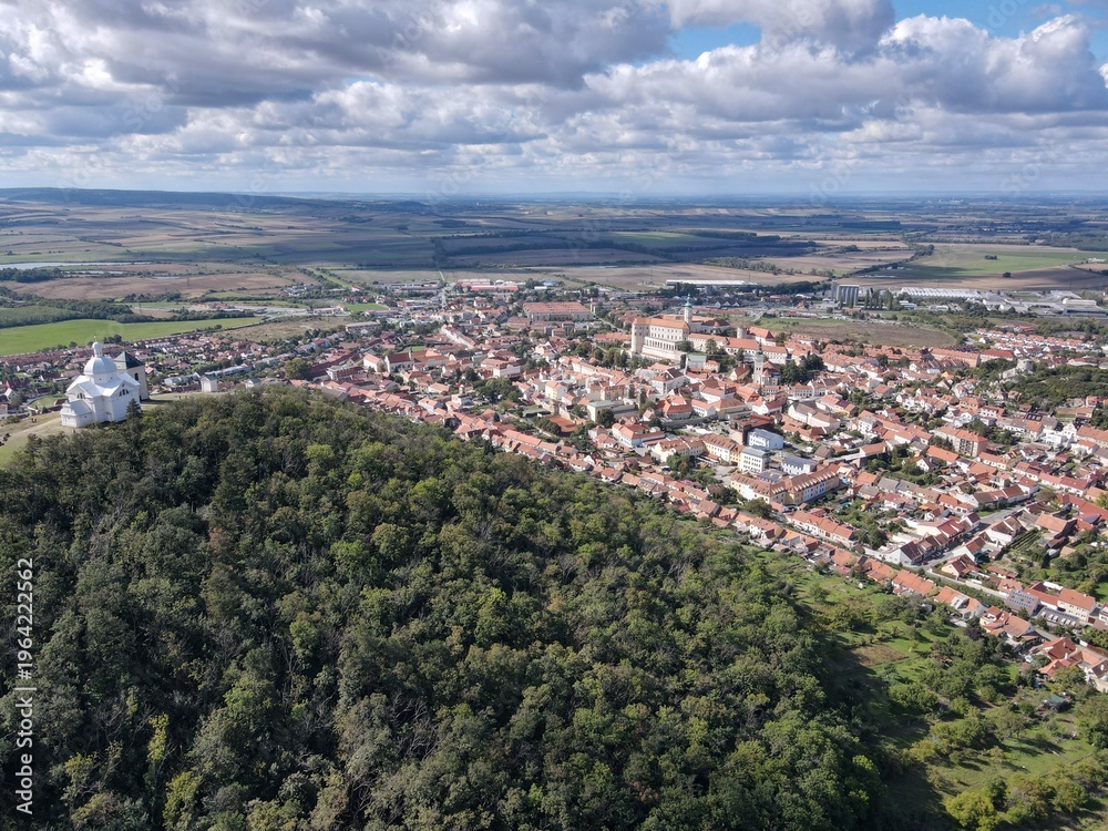 Fototapeta premium Aerial view of the historic center of Mikulov and the pilgrimage site of Svatý Kopeček. Sunny day with partly cloudy sky. Czech Republic, South Moravia.