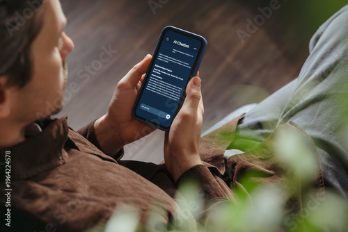 Close up of a man holding a smartphone, using an AI chatbot app for work, brainstorm a business project. Personal Artificial intelligence assistant helping with productivity. Space for text