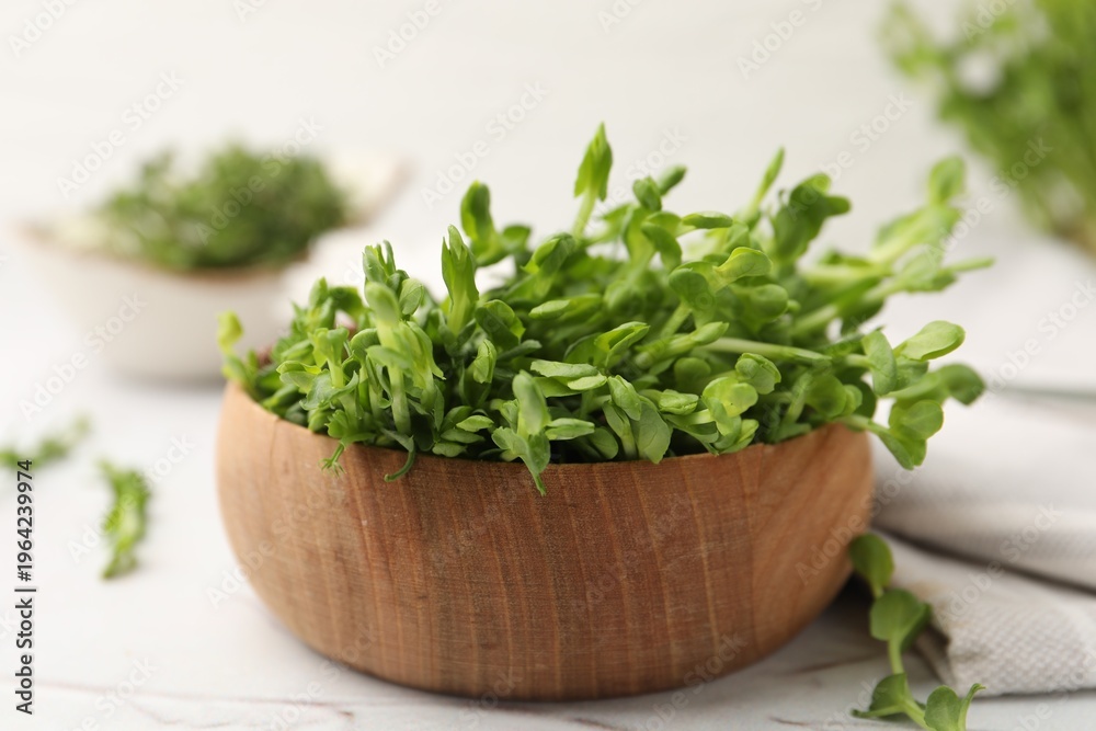 Fototapeta premium Fresh microgreens in bowl on white table, closeup