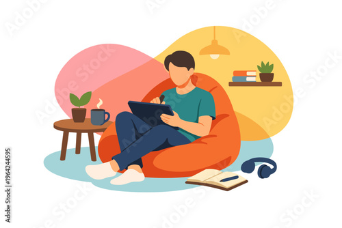 Young man sitting on bean bag chair using tablet computer.