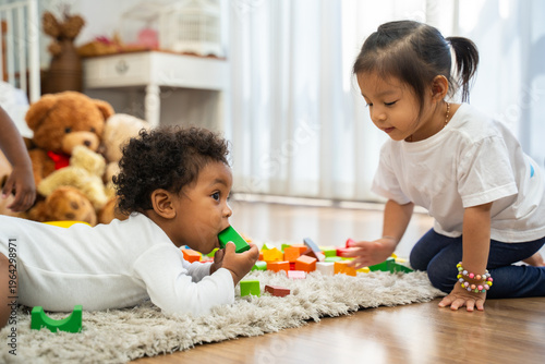 A baby is crawling on the floor and playing with a toy